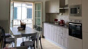 Une cuisine moderne avec un coin repas, dotée d’une grande fenêtre, d’appareils électroménagers intégrés et d’un sol carrelé.