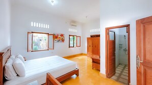 Ein Schlafzimmer mit Bett, Holzschrank und angrenzendem Badezimmer.