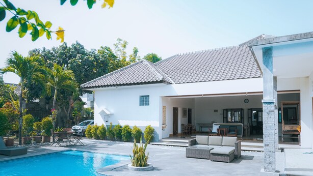 Ein modernes Haus mit Swimmingpool, Sitzgelegenheiten im Freien und einem Garten.