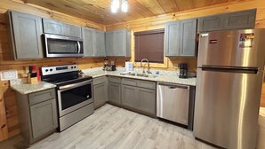 Une cuisine moderne dotée d’appareils électrom énagers en acier inoxydable, de meubles de couleur grise et d’un plafond en bois.