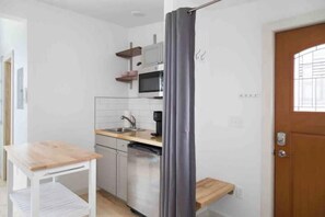 A compact kitchen with a microwave, sink, and a small wooden table. - Urban Luxury Loft: Parking+72”TV (Burlington)