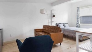 A modern bedroom with a bed, a desk, a sofa, and a chair. - Urban Luxury Loft: Parking+72”TV (Burlington)