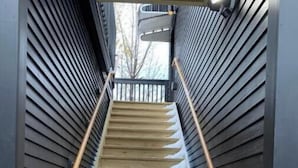 A wooden staircase with metal handrails, leading to a balcony. - Urban Luxury Loft: Parking+72”TV (Burlington)