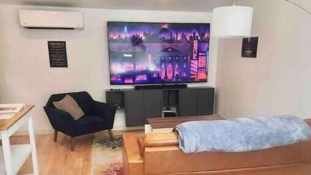 A modern bedroom with a bed, a sofa, a desk, and a TV. - Urban Luxury Loft: Parking+72”TV (Burlington)