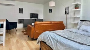 A modern bedroom with a bed, a desk, a TV, and a sofa. - Urban Luxury Loft: Parking+72”TV (Burlington)