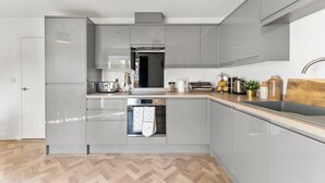 A modern kitchen with grey cabinets, a built-in oven, and a wooden countertop. - Spacious and Stylish Abode in Nottingham Sleeps 14 (Nottingham)