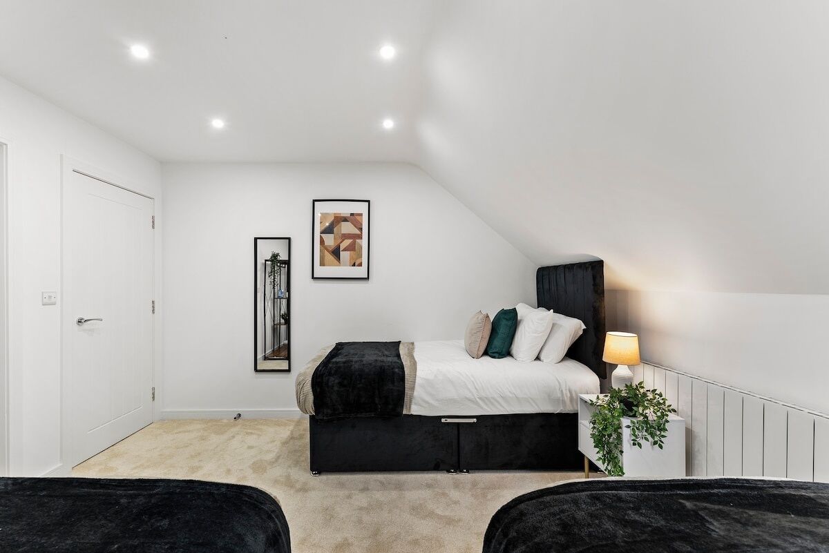 Un dormitorio con cama, mesita de noche, lámpara y un cuadro en la pared.
