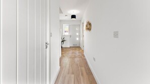 A hallway with a wooden floor, white walls, and a door at the end. - Spacious and Stylish Abode in Nottingham Sleeps 14 (Nottingham)