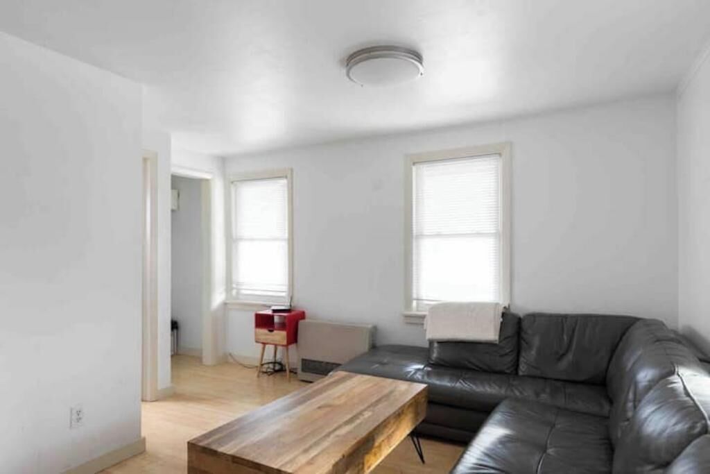 Ein modernes Wohnzimmer mit einer Ledersofa, einem Holztisch und einem roten Beistelltisch.