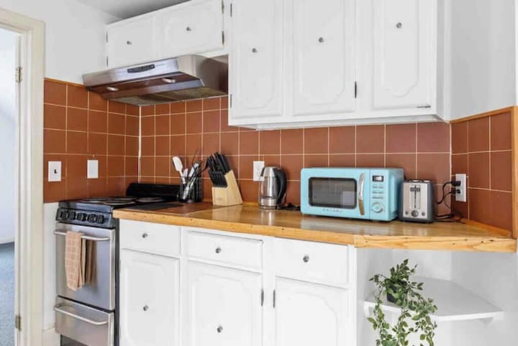 Eine Küche mit weißen Schränken, einer Mikrowelle, einem Toaster und einem Herd.