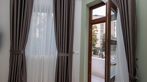 Una habitación con una puerta que da a un espacio exterior, con cortinas y vista a la calle.