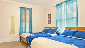 Ein Schlafzimmer mit zwei Betten, einem Spiegel und einem Fenster mit blauen Vorhängen.