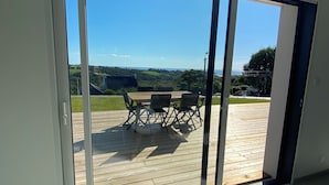 A room with a sliding glass door leading to an outdoor deck with a table and chairs.