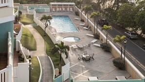 A resort pool area with a view of the ocean, surrounded by palm trees and a clear sky. - #17 REAL Beachfront 3BR Retreat @ Isabela Beach Ct (Isabela)