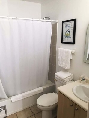 A bathroom with a shower curtain, a toilet, a sink, and a framed picture on the wall.