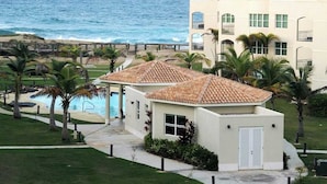 A beachfront hotel with a pool, palm trees, and ocean views. - #8 Beach Apt 2BR, 2BA - Jobos, Montones, Shacks (Isabela)
