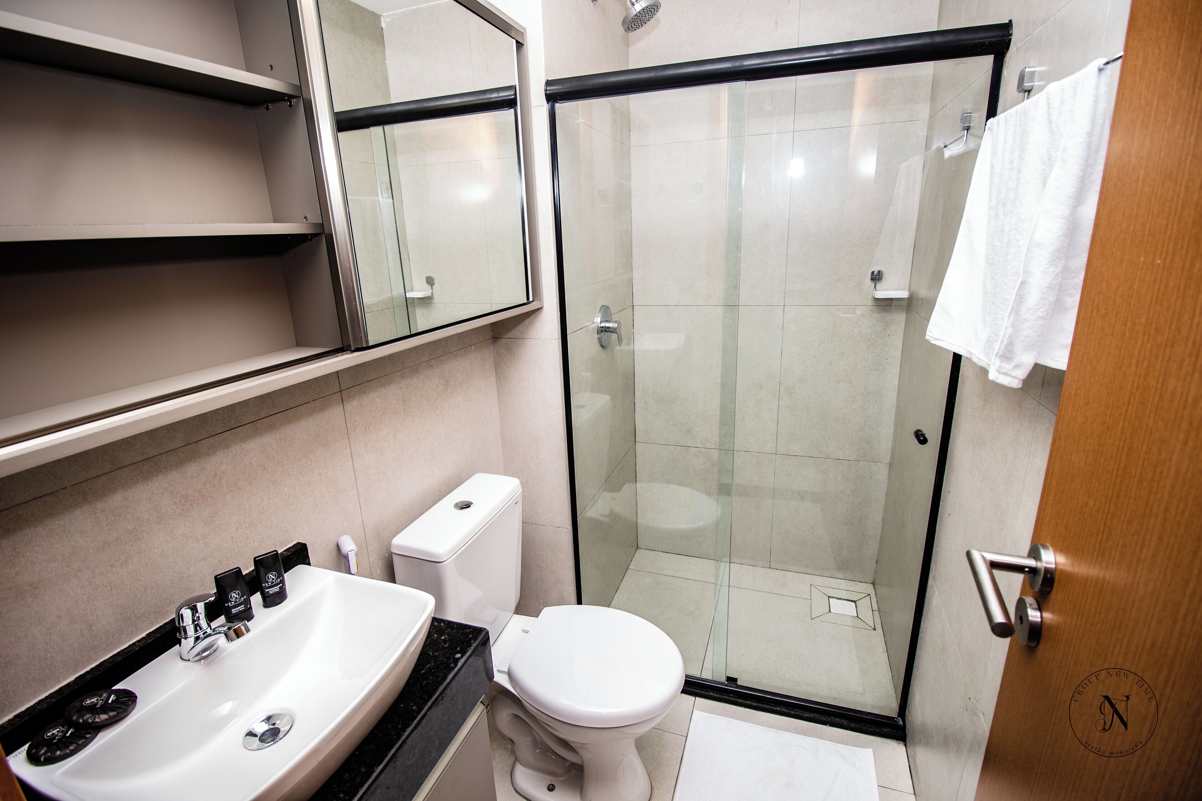 A modern bathroom with a glass-enclosed shower, a white sink, and a toilet.