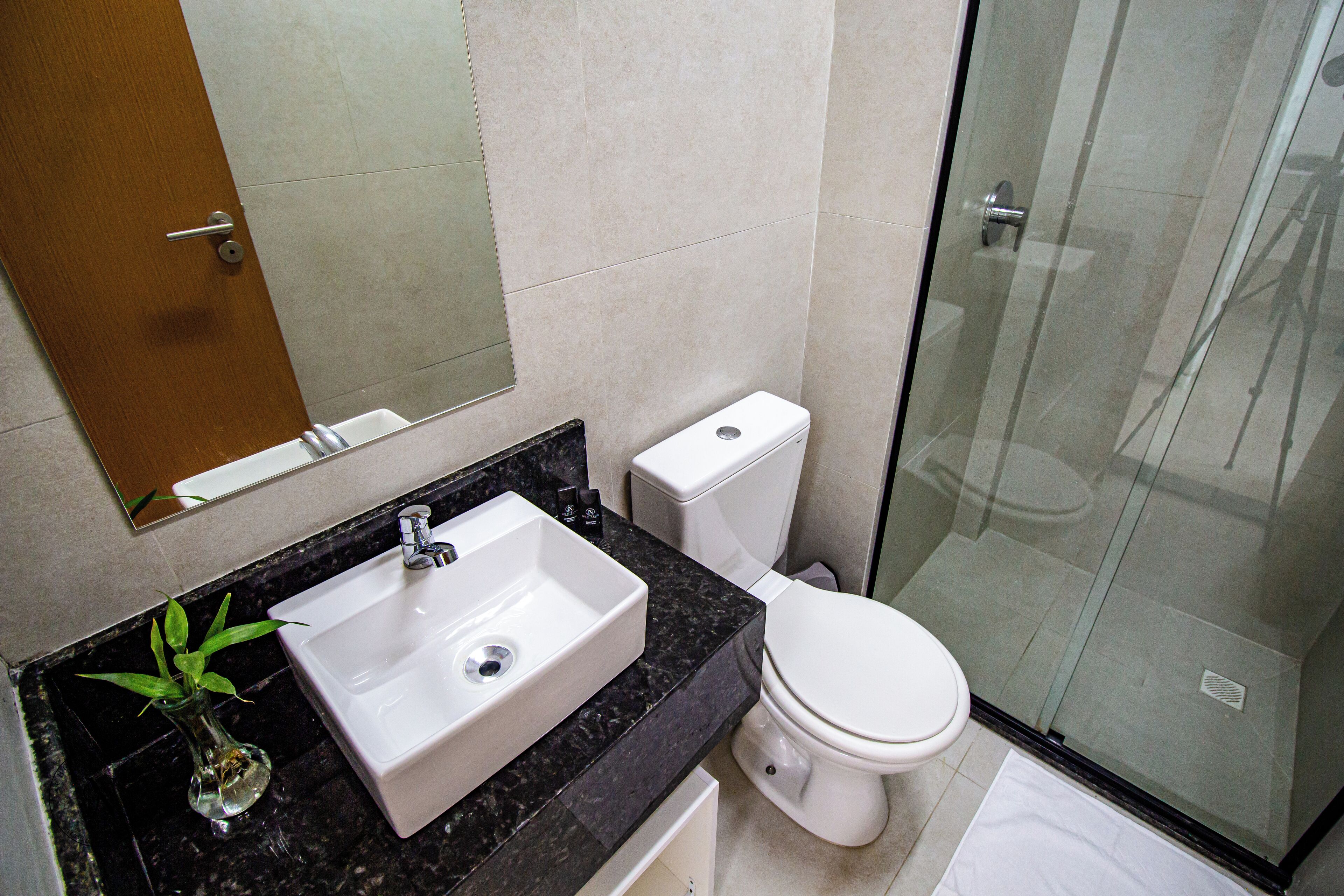 Baño con lavamanos de mármol, inodoro y cabina de ducha de vidrio.