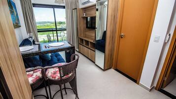 Habitación compacta con una mesa de comedor, dos sillas, un televisor y un ventanal con vistas al exterior.