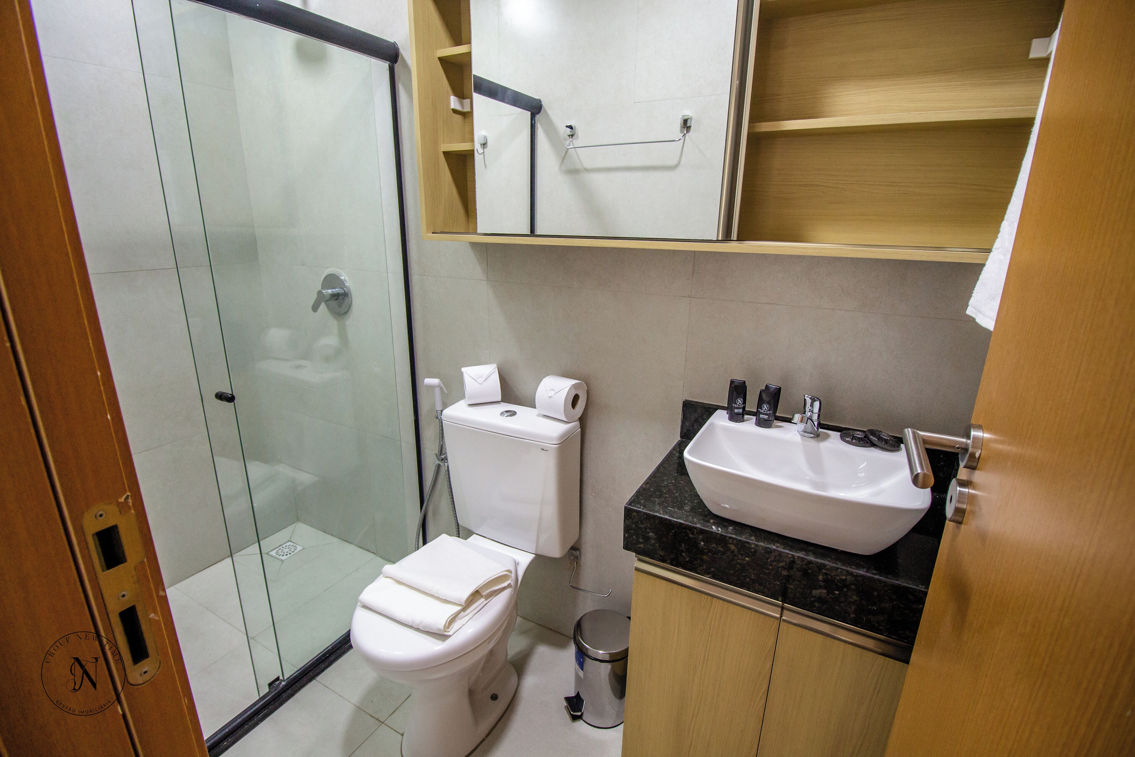 A bathroom with a glass shower enclosure, a toilet, a sink, and a mirror above the mirror cabinet.