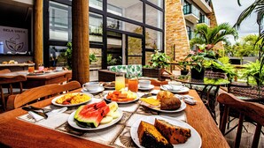 An outdoor dining area with tables set for breakfast, featuring plates of food, drinks, and a view of the building's interior. - Bela Vista Beach By New Time (Ipojuca)