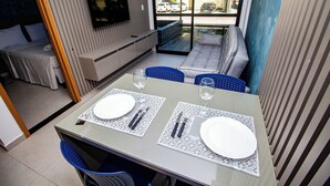 A dining area with a table set for two, a sofa, and a TV mounted on the wall. - Bela Vista Beach By New Time (Ipojuca)