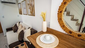 A modern living room with a wooden dining table, a vase with dried plants, and a large mirror with a unique wooden frame. - Bela Vista Beach By New Time (Ipojuca)