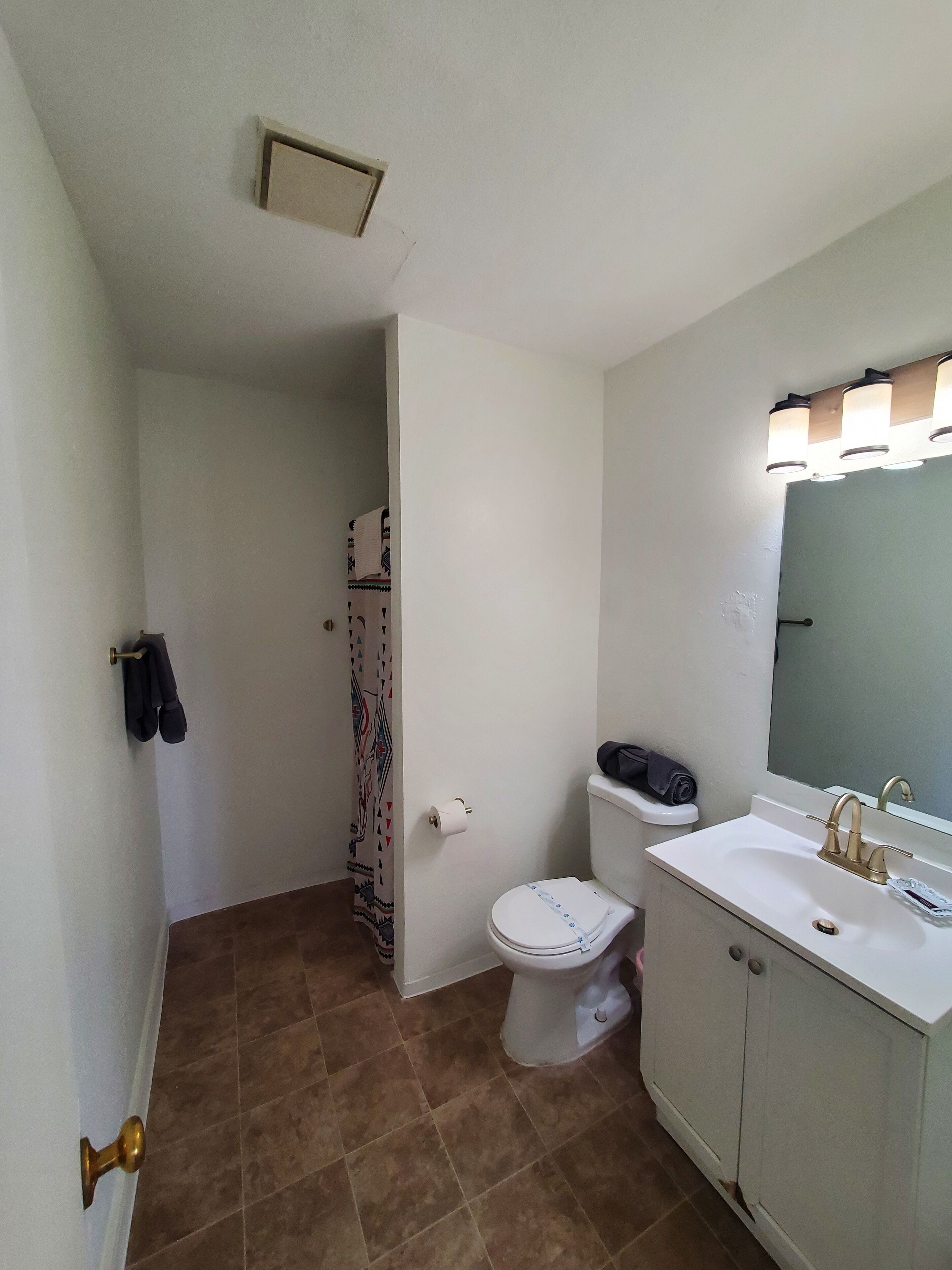 Un baño con inodoro, lavamanos y cortina de ducha.