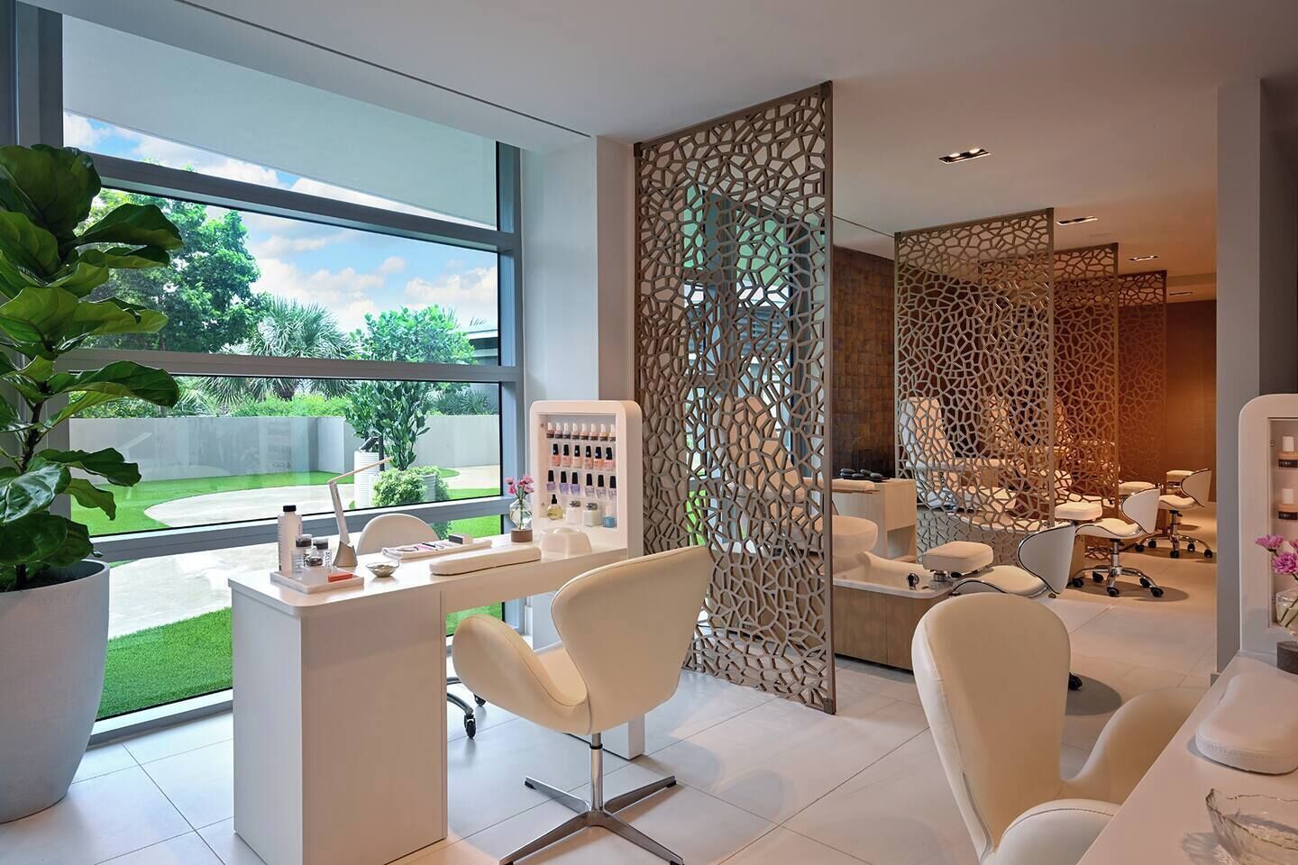 A modern salon with a large window, a reception desk, and a seating area.