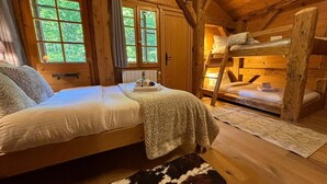 A cozy cabin-style room with a bed, a bunk bed, and a window with curtains. - Chalet Ski-In Plagnat, Ardent  (Montriond)
