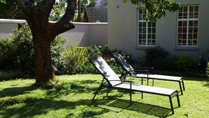 Un giardino con due poltrone e un albero.