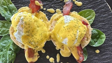 A breakfast dish with eggs, bacon, and spinach on a dark plate.