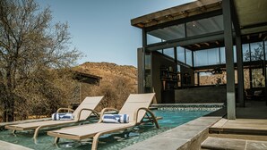 A pool area with lounge chairs and a bar area visible through large windows.
