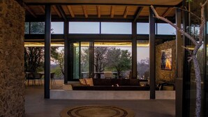 A modern interior with large windows, a stone wall, and a seating area with a fire feature.
