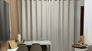 Ein modernes, helles Schlafzimmer mit einem Holzbüro, einem Bett und einem kleinen Tisch mit Lampe.