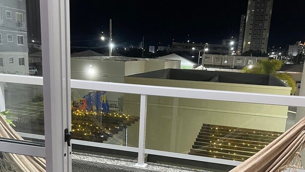 Ein Balkon mit einer Hängematte, Blick auf die nächtliche Skyline und eine Treppe, die zu einer oberen Ebene führt.