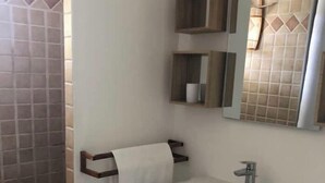 A bathroom with a white sink, wooden shelves, and a mirror.