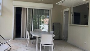 A balcony with a table and chairs, a sliding glass door, and a view of the outside.