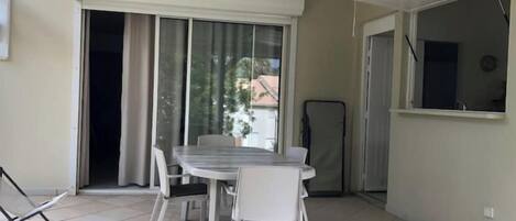 A balcony with a table and chairs, a sliding glass door, and a view of the outside.