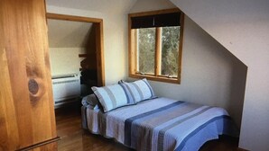 A bedroom with a sloped ceiling, a window, a bed with a striped bedspread, and a wooden door. - Beautiful waterfront home nestled on 4acres on Indian Lake!
A perfect getaway!
 (Whiting)