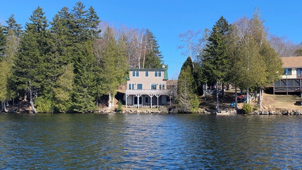 A two-story house with a balcony, surrounded by trees and a lake. - Beautiful waterfront home nestled on 4acres on Indian Lake!
A perfect getaway!
 (Whiting)