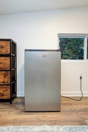 Un réfrigérateur moderne en acier inoxydable, dans une pièce dont le sol est recouvert de parquet et qui possède une fenêtre.