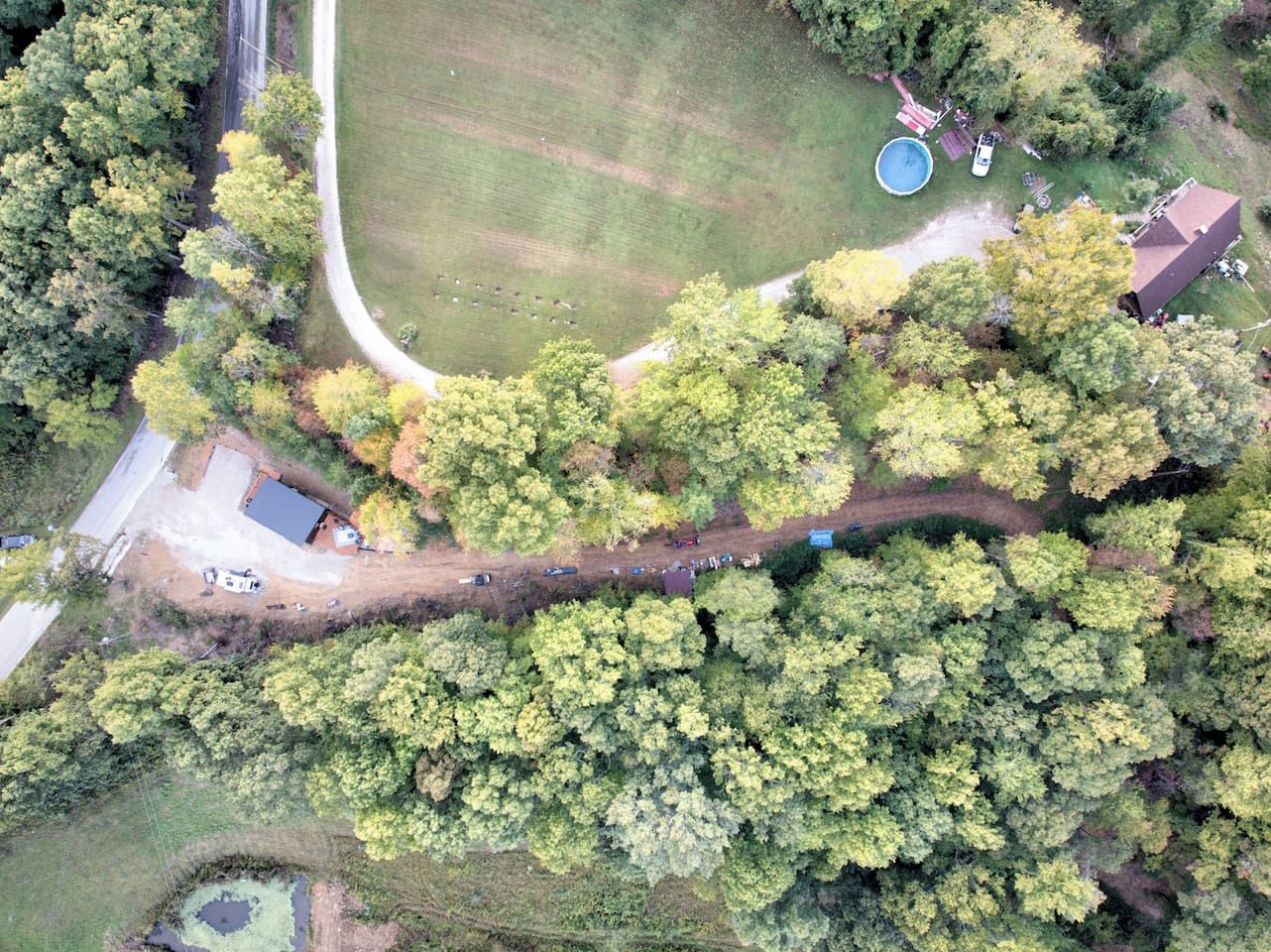 Vista aérea de una propiedad con piscina, zona vallada y camino de acceso.