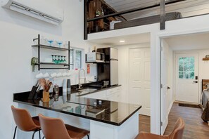 Una cocina moderna con una isla central, taburetes de bar y un comedor con vistas al exterior.