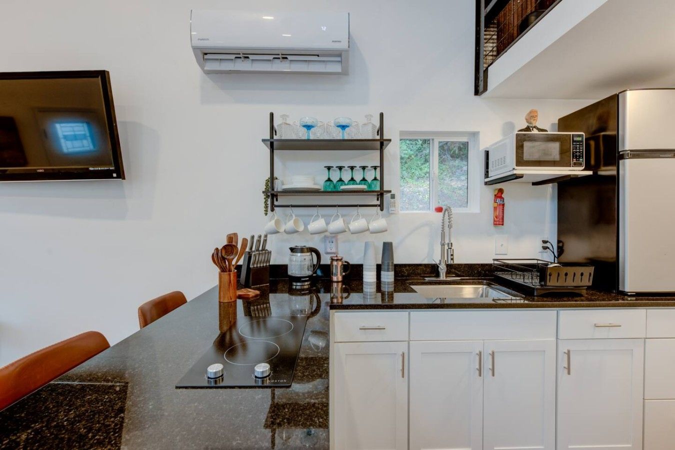 A modern kitchen with white cabinets, a black countertop, a built-in microwave, and a coffee maker.