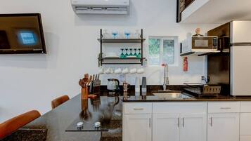A modern kitchen with white cabinets, a black countertop, a built-in microwave, and a coffee maker.