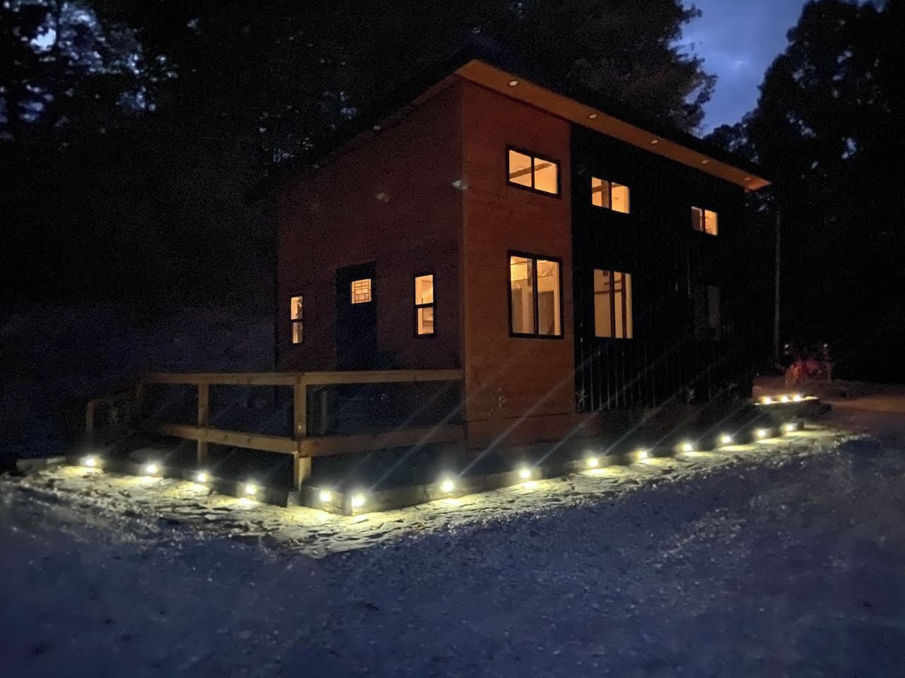 A modern building with a wooden deck and a series of lights along the front.