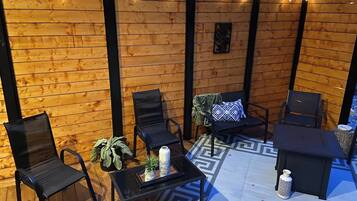 A wooden deck with outdoor seating, including chairs and a table, and a patterned rug.