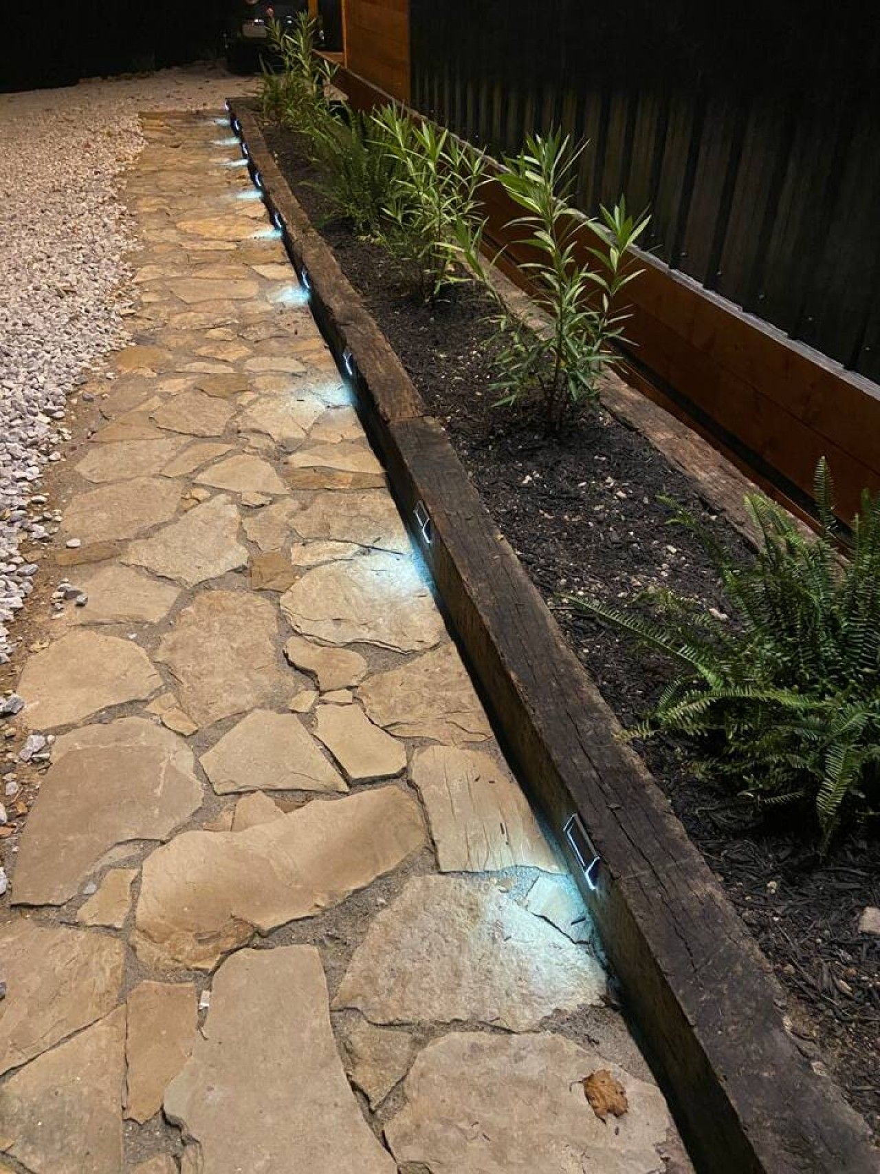 Un camí de pedra amb una caixa de plantació de fusta plena de plantes.