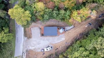 An aerial view of a property with a single building, a gravel driveway, and a parked vehicle.